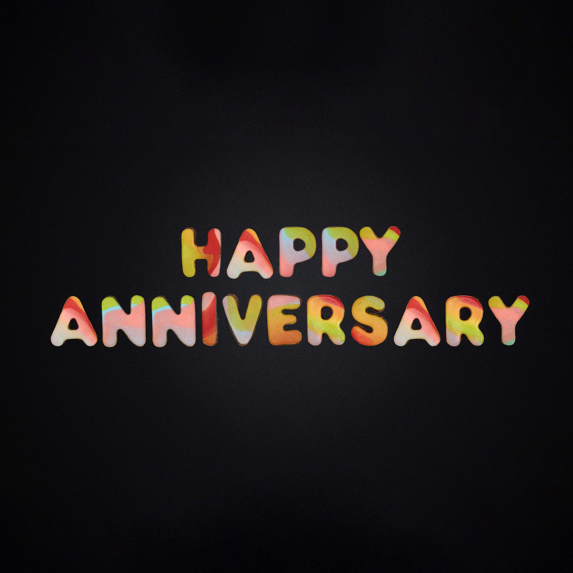 A black background with the words happy anniversary written in colorful letters