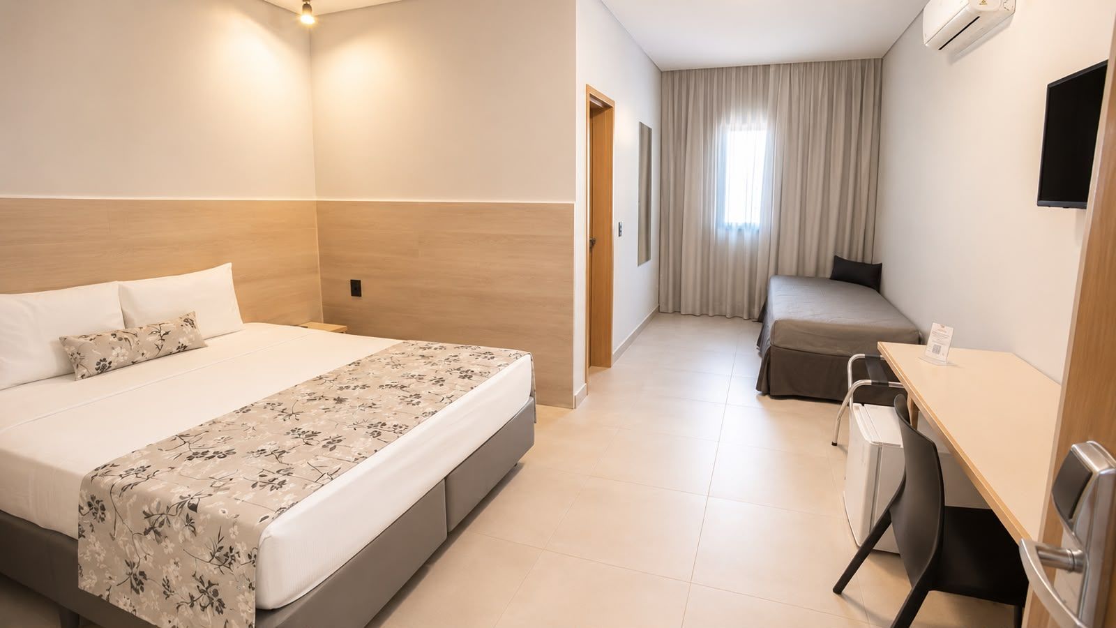 roupa de cama dourada estampada, uma bandeja de café da manhã em uma das camas e luminárias de parede com luz quente.