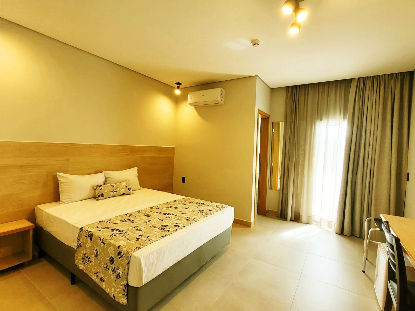 quarto luxo com cama de casal, cortinas, ar condicionado, mesa de trabalho