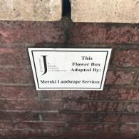 A white sign on a red brick wall reads: