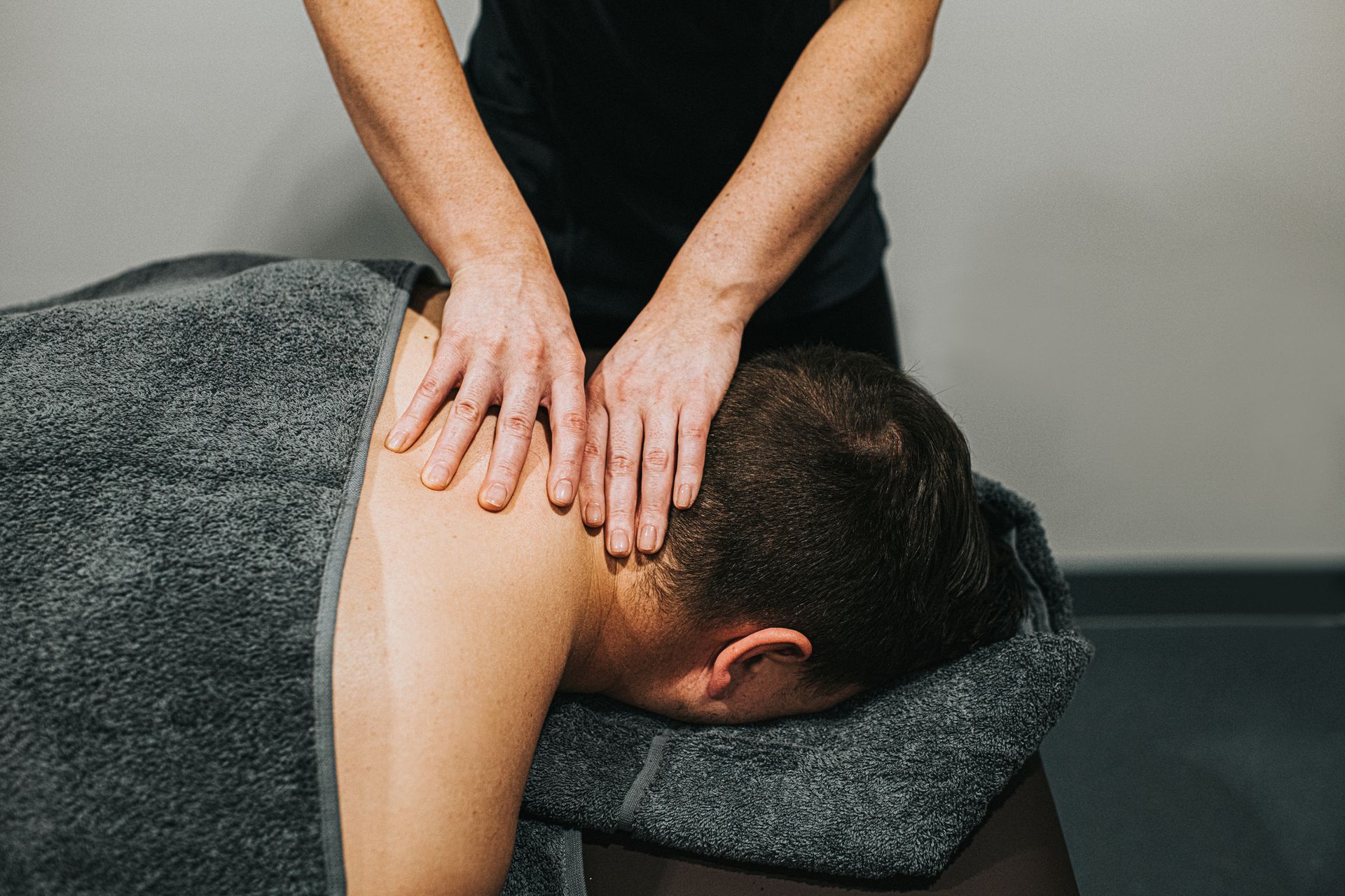 Hands of a person pressing on the recipient's shoulders.