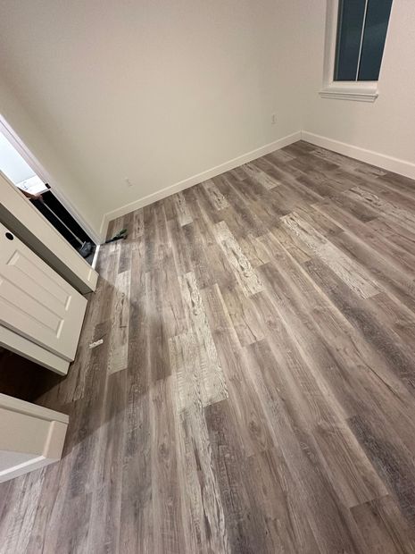 Empty room with gray wood-look flooring, white walls, and a window.