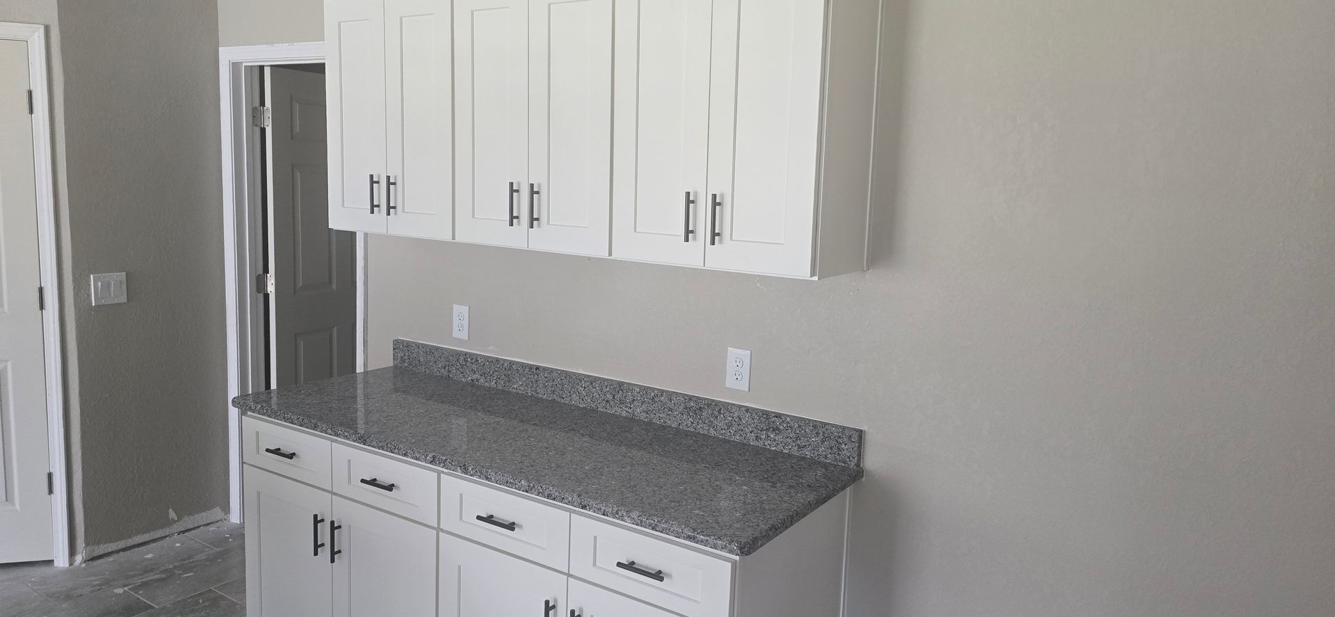 Kitchen with white cabinets, gray granite countertop, and stainless steel refrigerator.