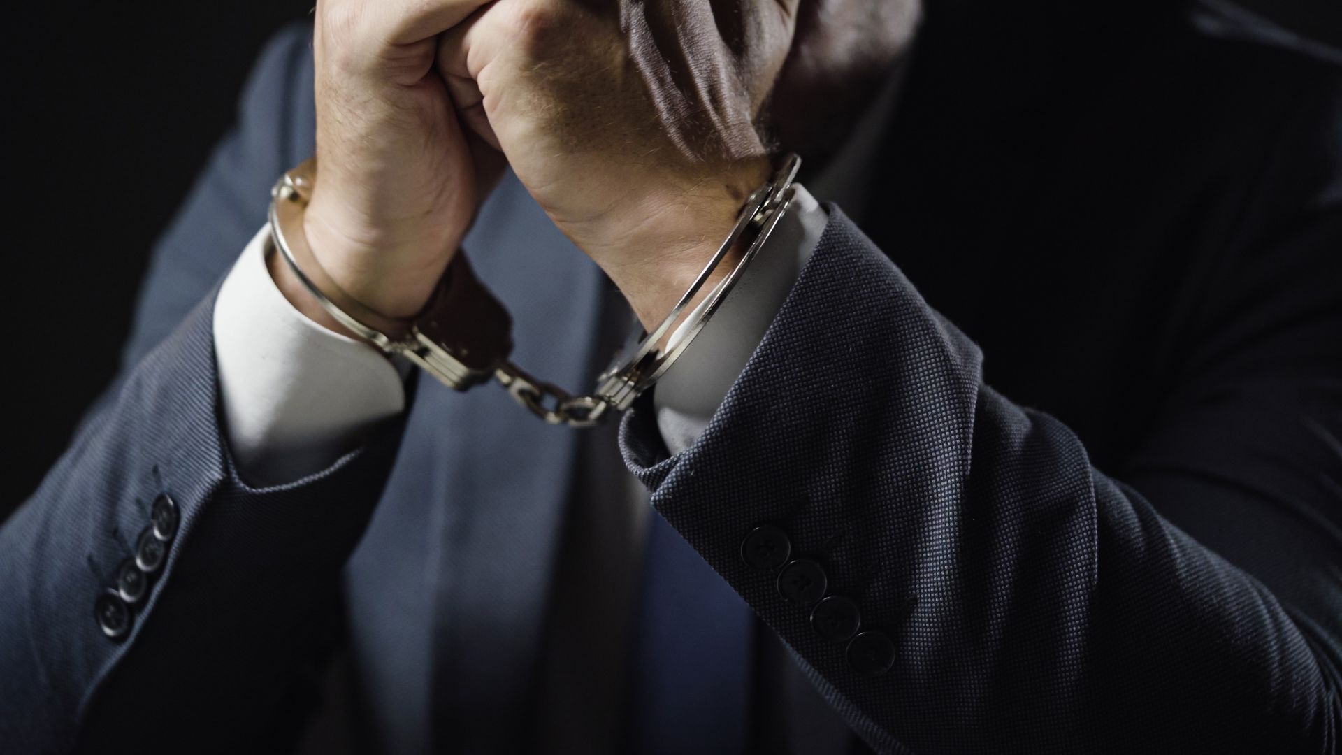 A man in a suit is wearing handcuffs.