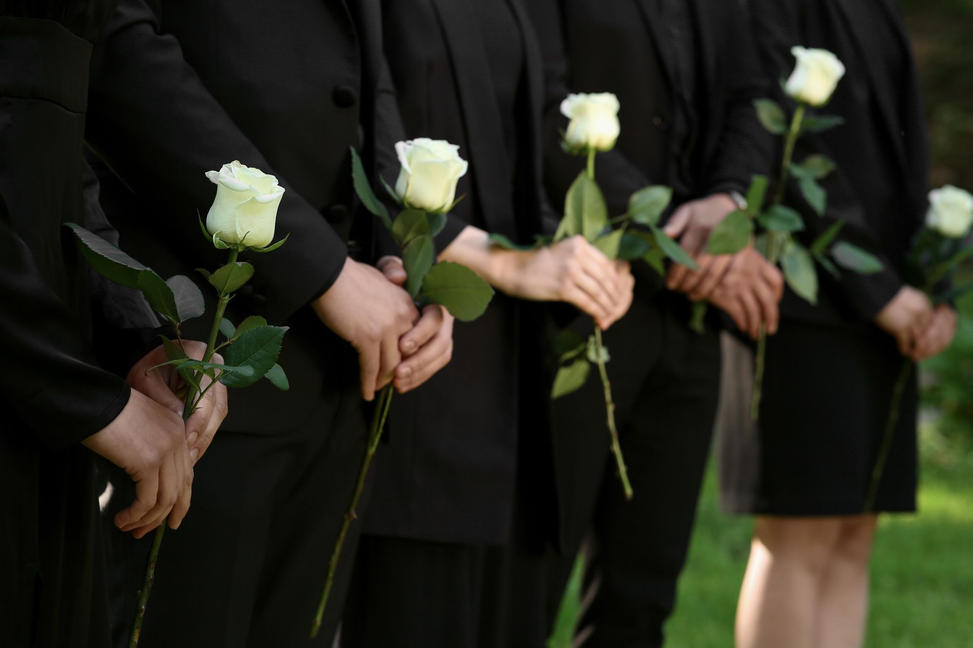 A Group Of People In Black Suits Are Holding White Roses In Their Hands — Territory Funerals In Yarrawonga, NT