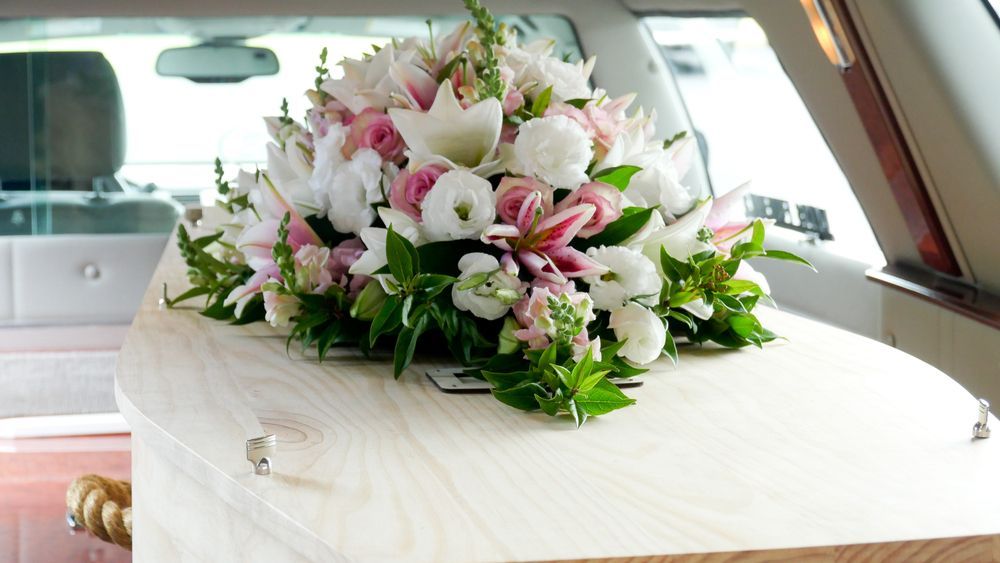 A Coffin With Flowers On Top Of It Is In A Limousine — Territory Funerals In Yarrawonga, NT