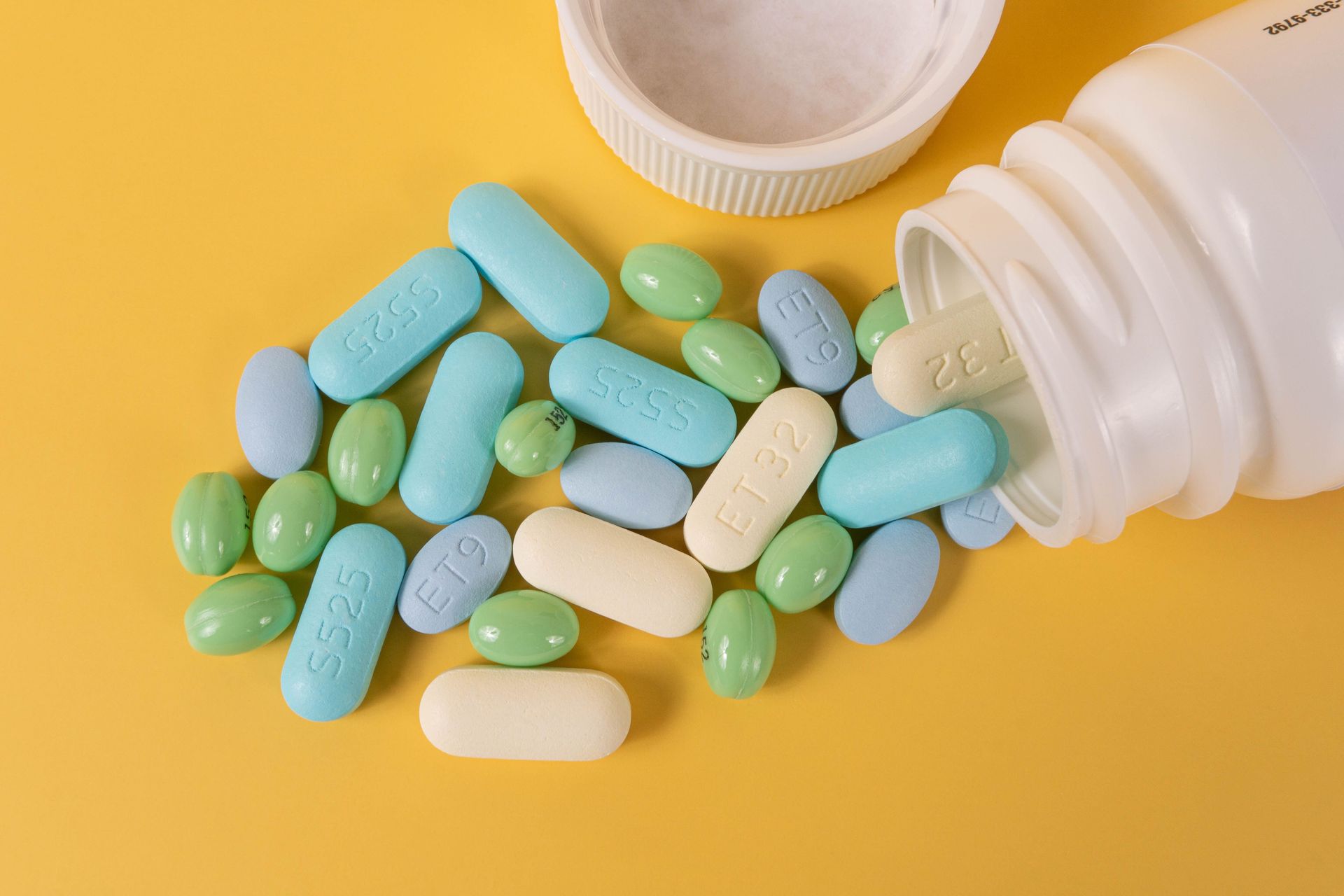 Scattered blue, green, and white pills spilling from a white bottle on a yellow background