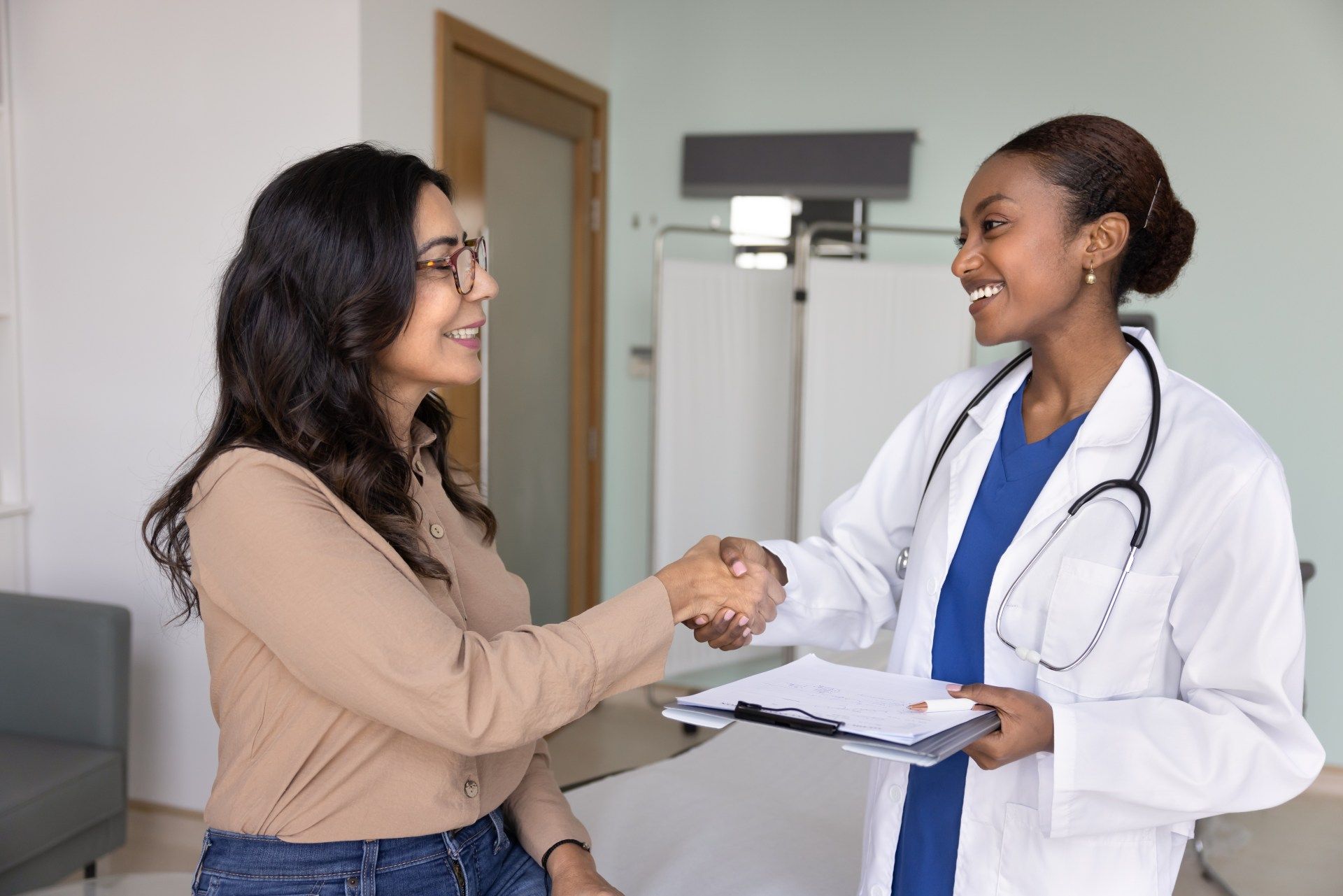 Patient shaking hands with a doctor in a clinic exam room