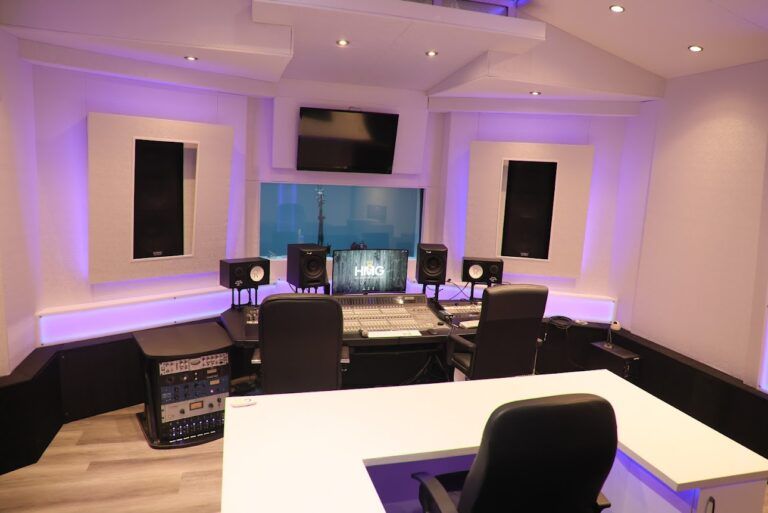 Modern music recording studio with mixing desk, speakers, monitors, and purple accent lighting