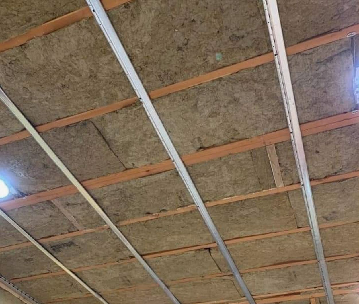 Ceiling insulation with metal supports and wooden beams.