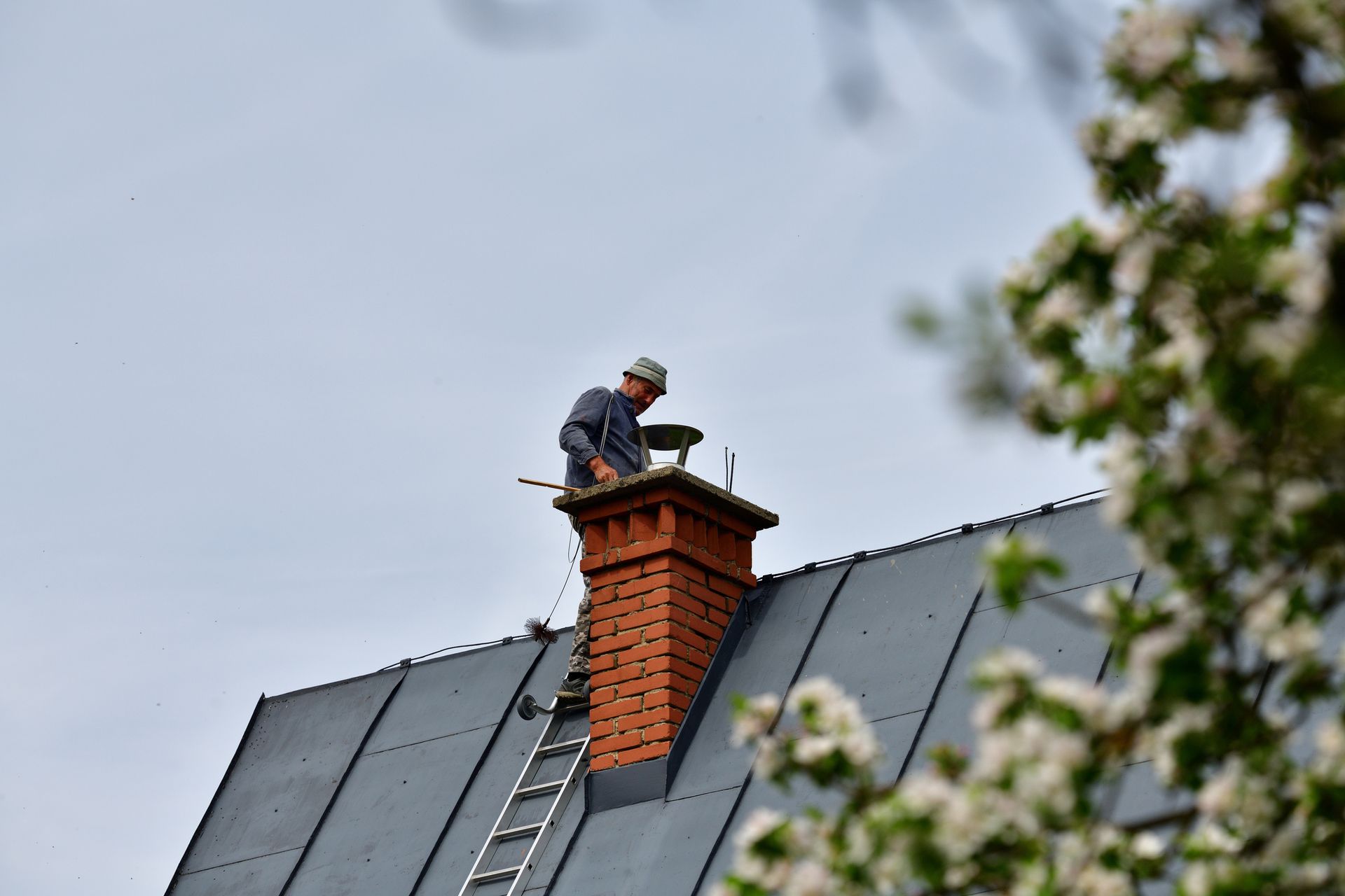 A man is working on a chimney on the roof of a house.