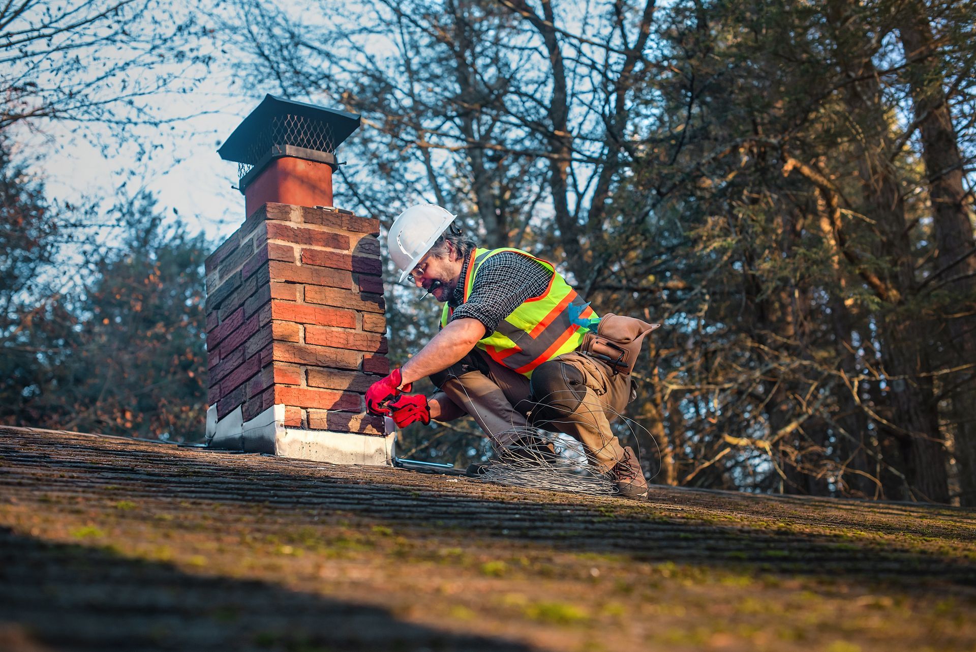 A man is working on a chimney on top of a roof. A man is working on a chimney on top of a roof.