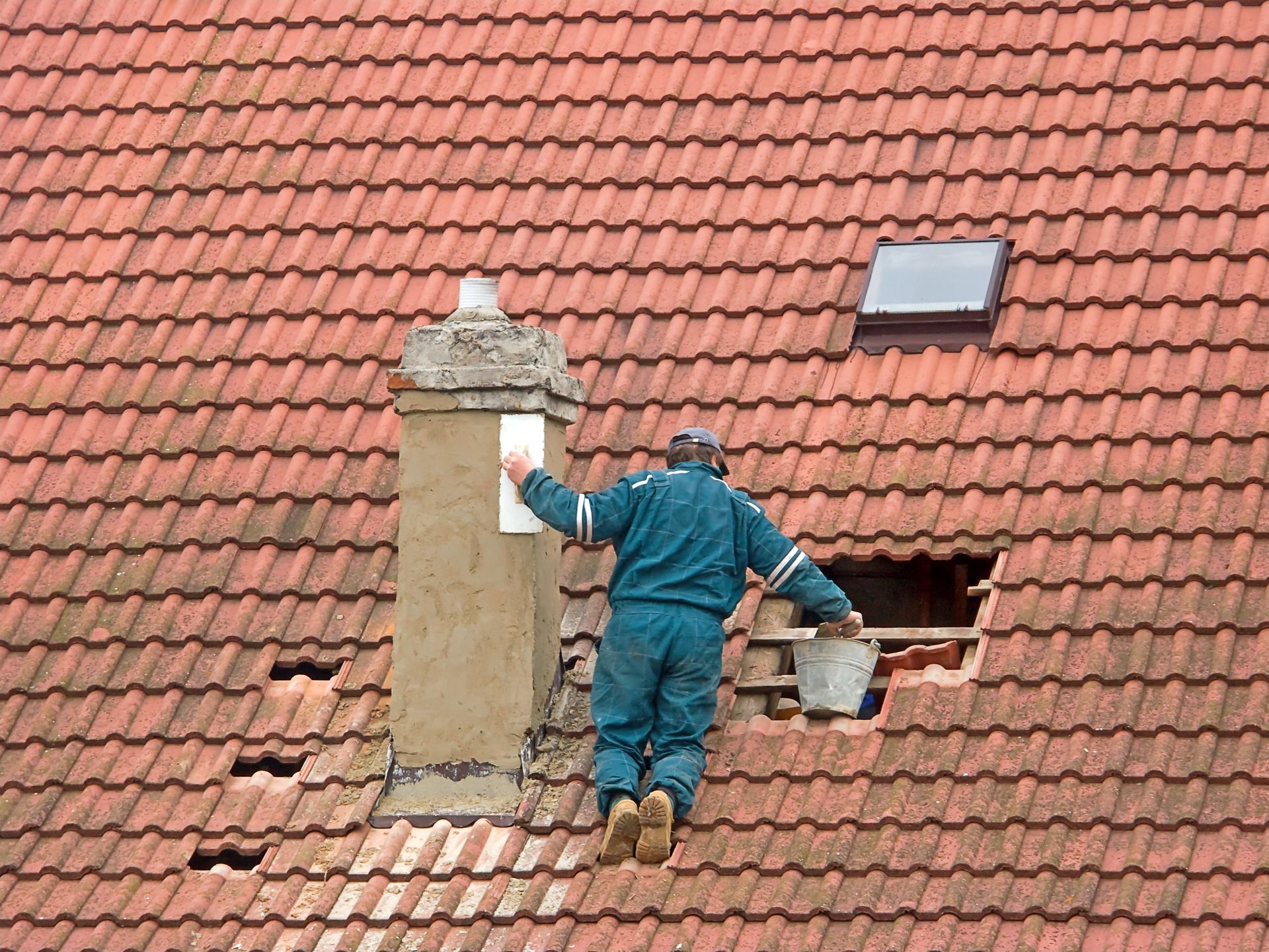 A man is standing on top of a tiled roof.