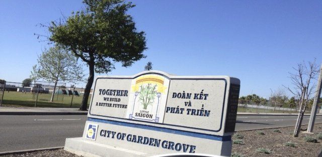 City of Garden Grove sign with text in English and Vietnamese, trees, and clear blue sky.