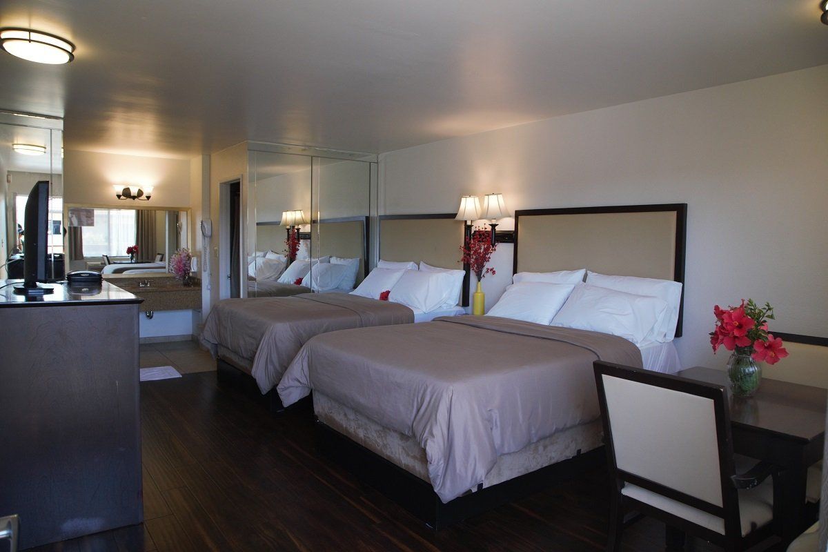 Hotel room with two queen beds, neutral tones, and desk.