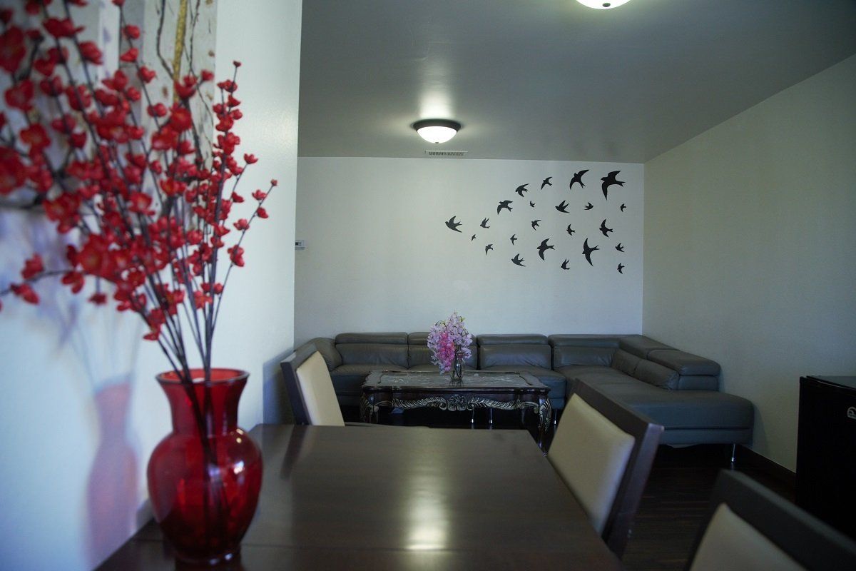 Dining room with red floral arrangement, sectional sofa, bird wall art.