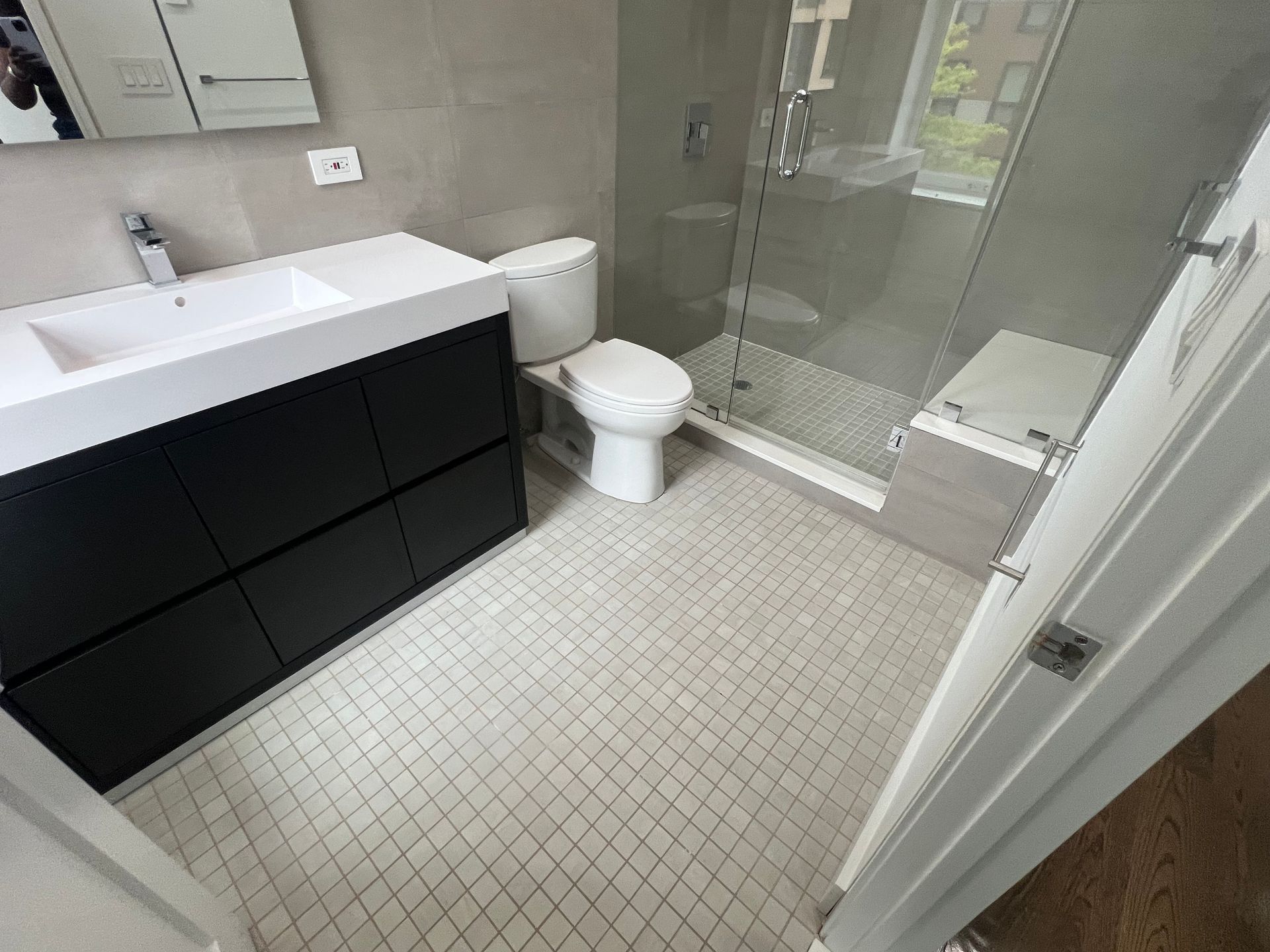 Modern bathroom with black vanity, white toilet, and glass shower enclosure