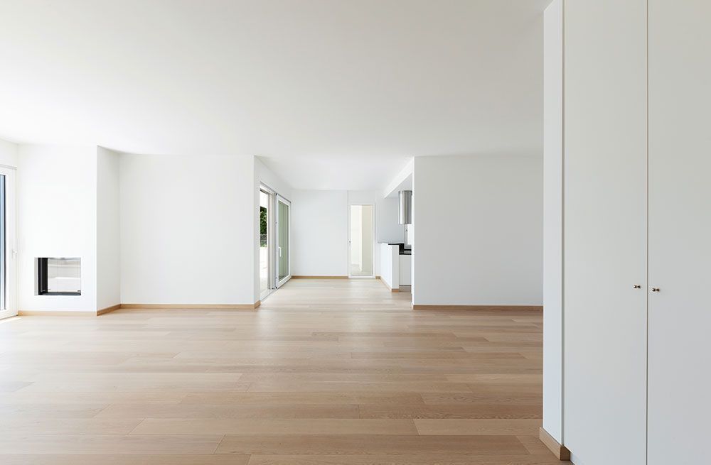 Bright empty modern room with light wood floors, white walls, and built-in closet doors