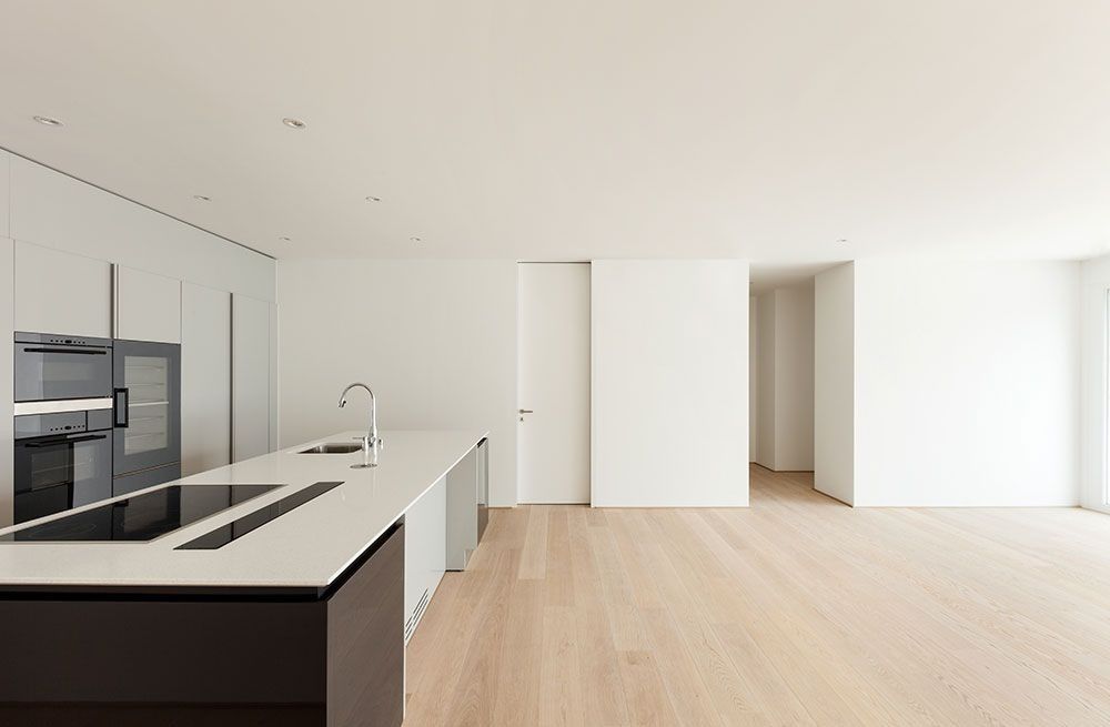 Bright modern kitchen with white cabinets, wood floors, and a large island