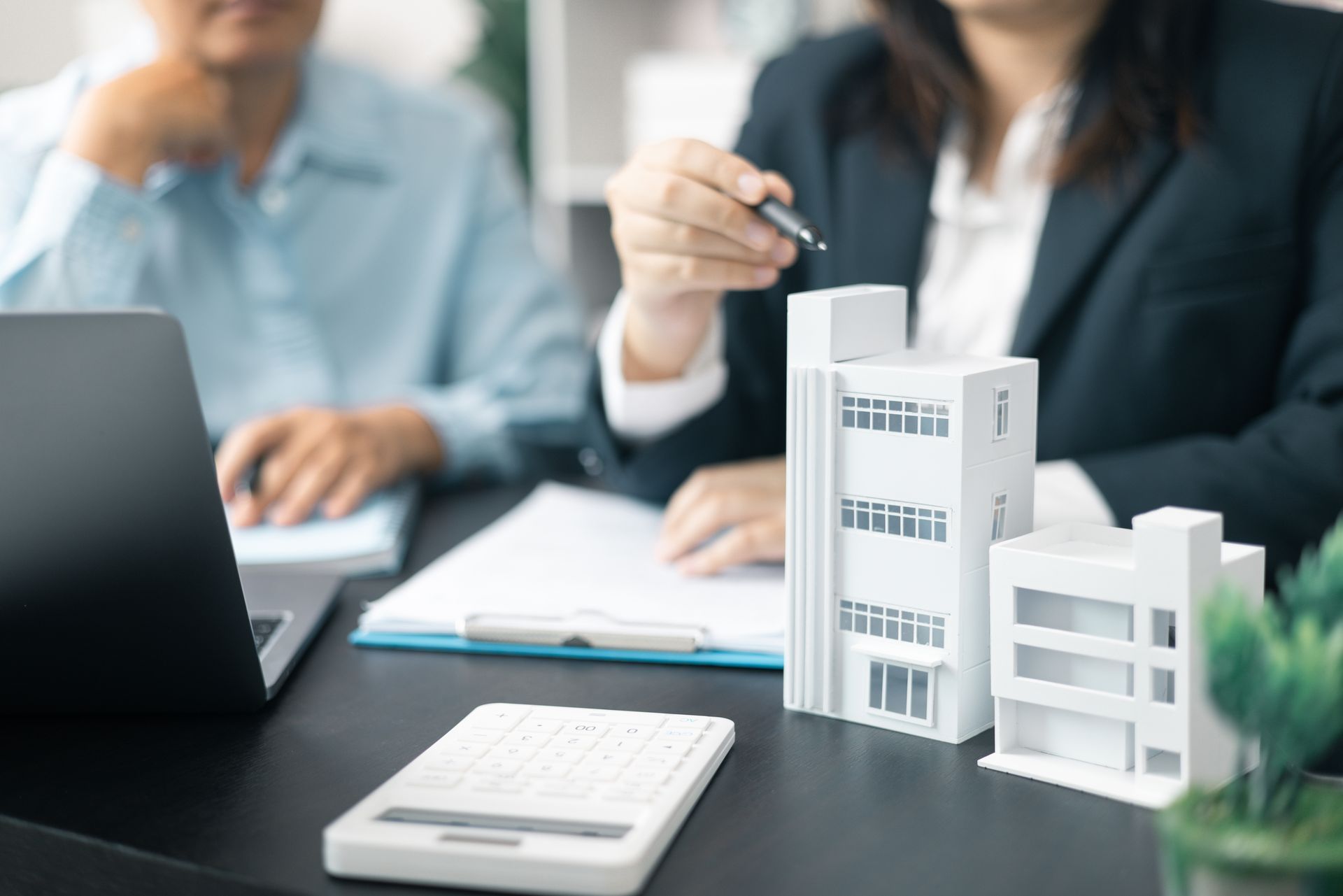 Business meeting with laptop, documents, and architectural building model on a desk