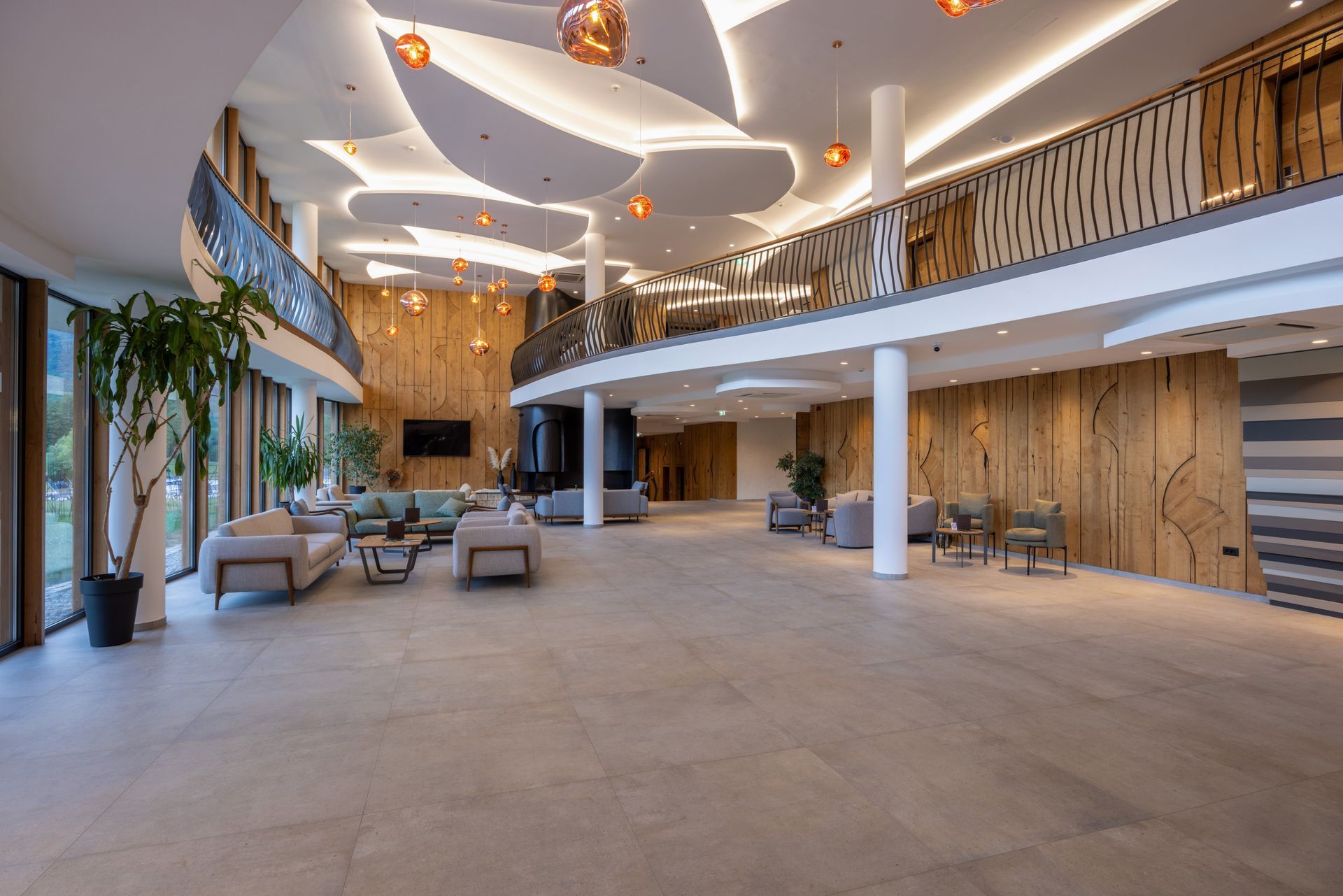 Spacious modern hotel lobby with curved ceiling, lounge seating, and large windows.