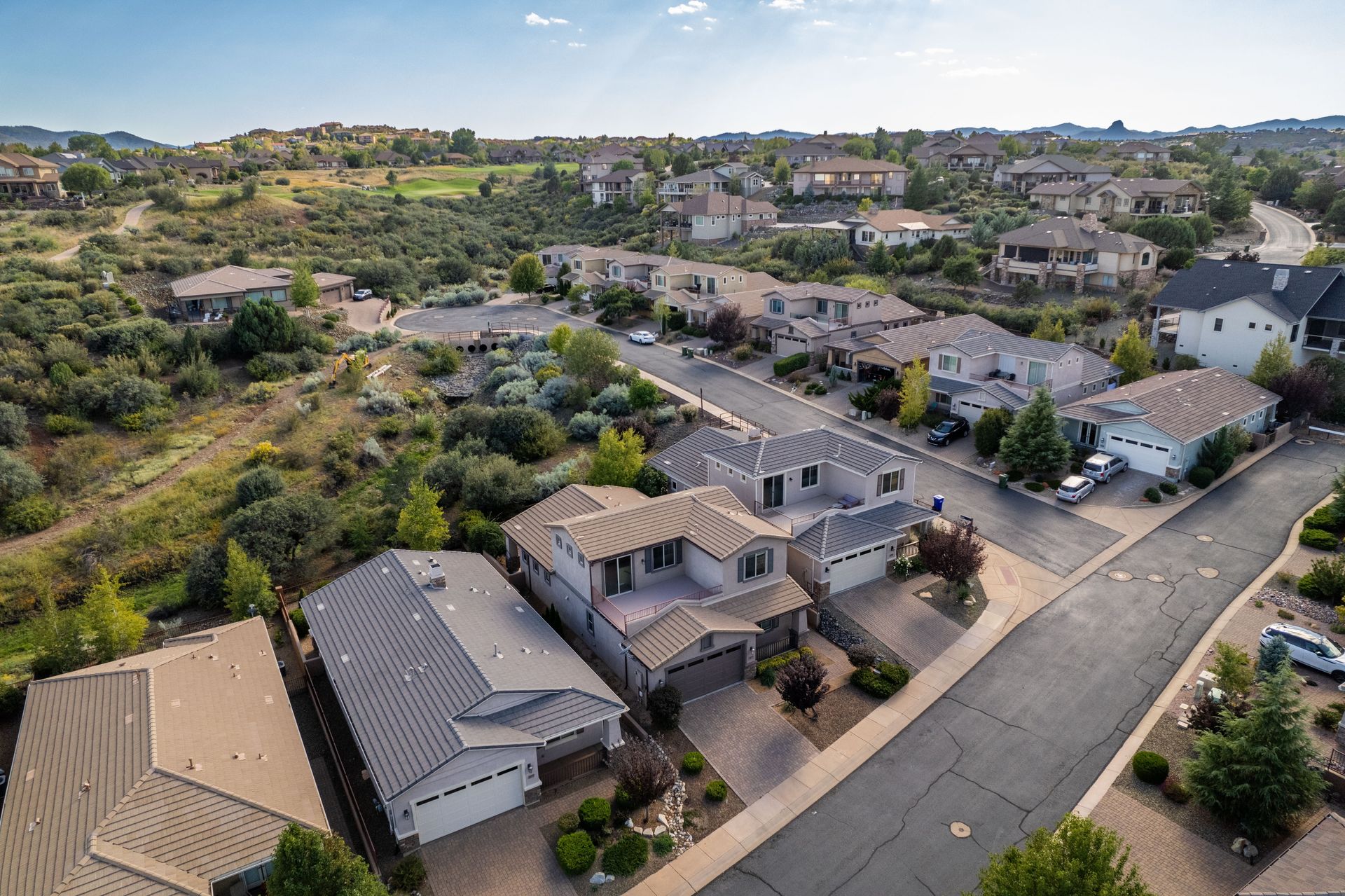 Aerial view of a suburban neighborhood with rows of houses, streets, and hills in the background