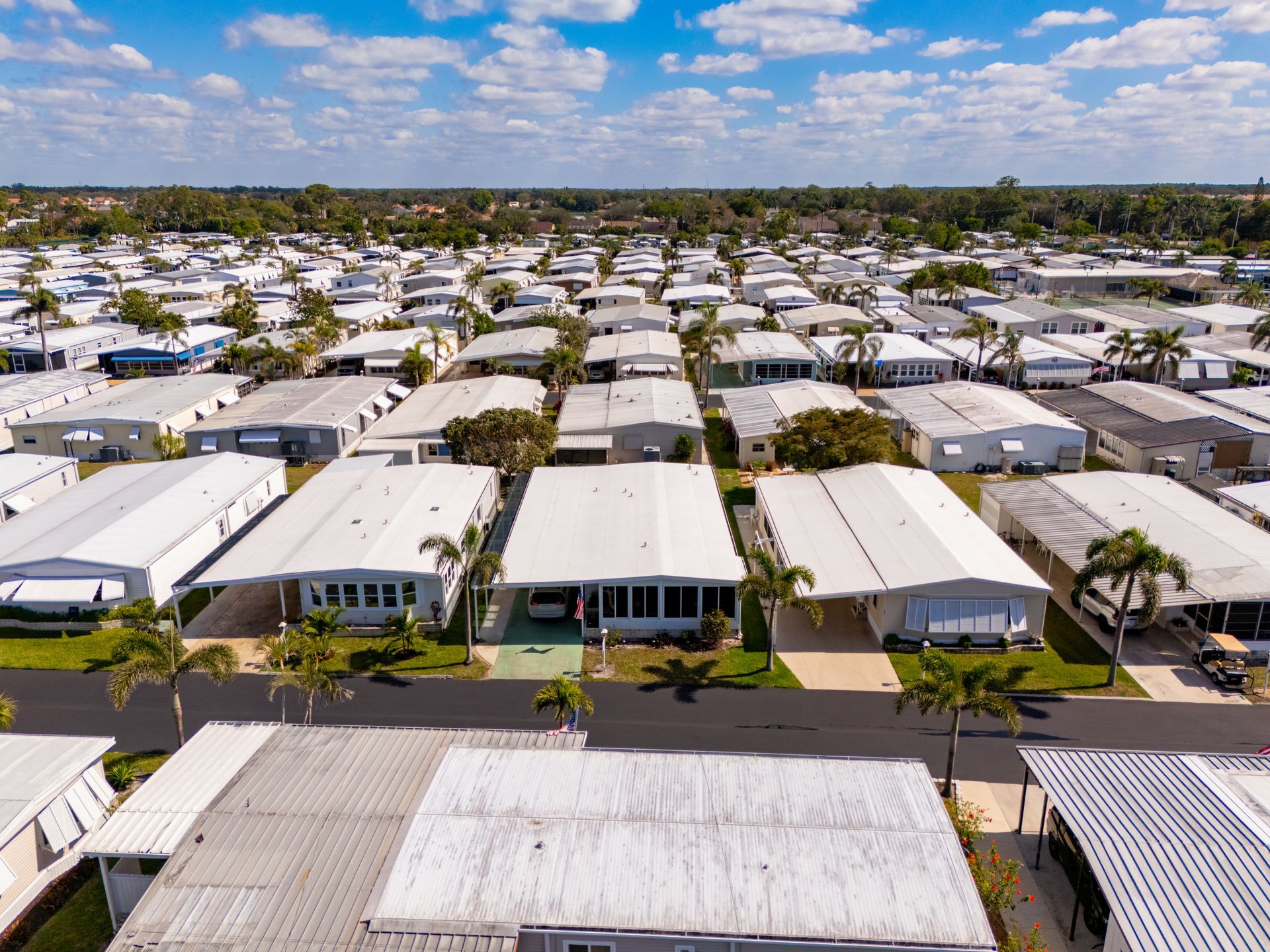 Aerial view of a neighborhood with rows of white-roofed houses under a blue sky