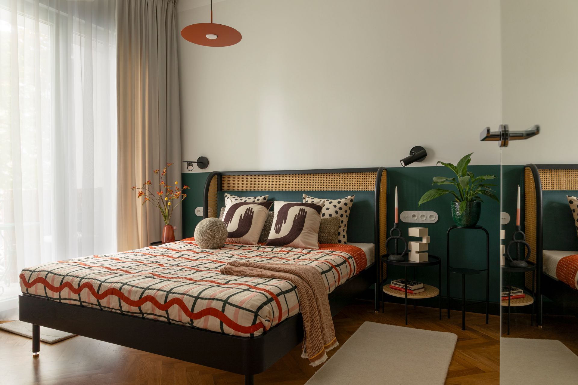 Modern bedroom with green walls, patterned bedspread, beige curtains, and potted plants by the bed