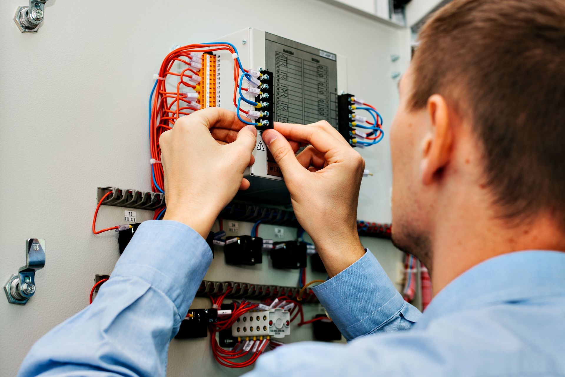 Technician wiring an electrical panel with multicolored cables