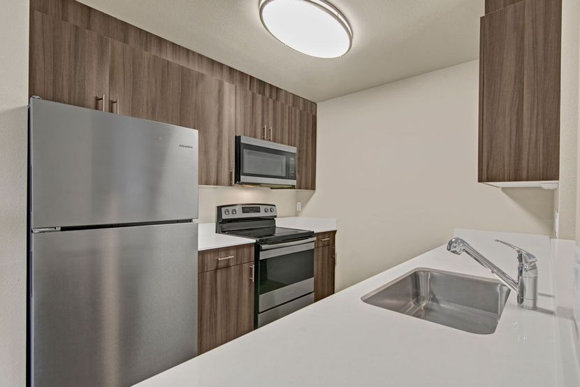 a kitchen with a sink , refrigerator , stove and microwave .