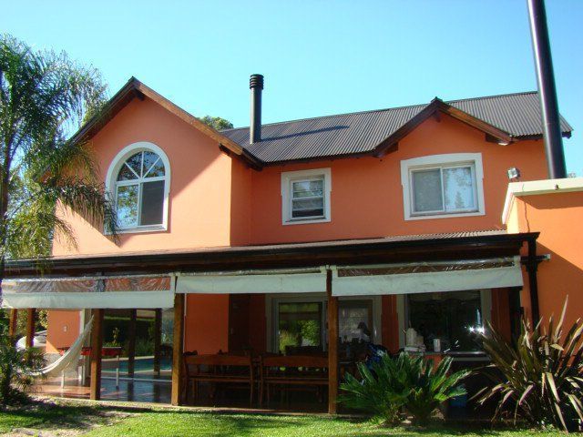 Casa naranja de dos plantas, con ventanas de marcos blancos y un porche delantero cubierto, a la luz del día