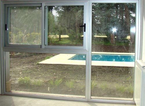 Puerta corredera de cristal con vistas al patio trasero y a la piscina