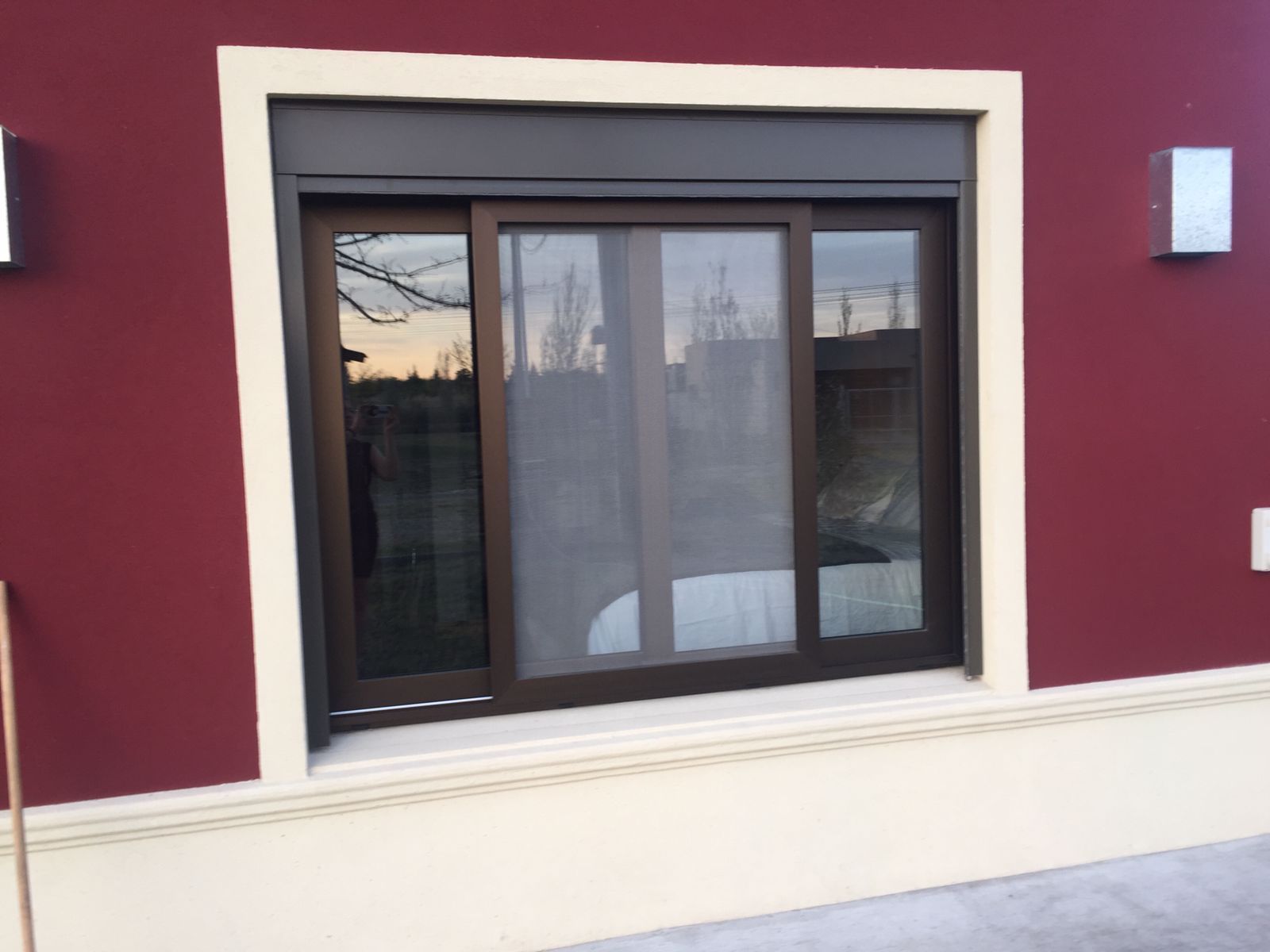 Ventana moderna en una pared exterior granate con molduras blancas y cristales reflectantes
