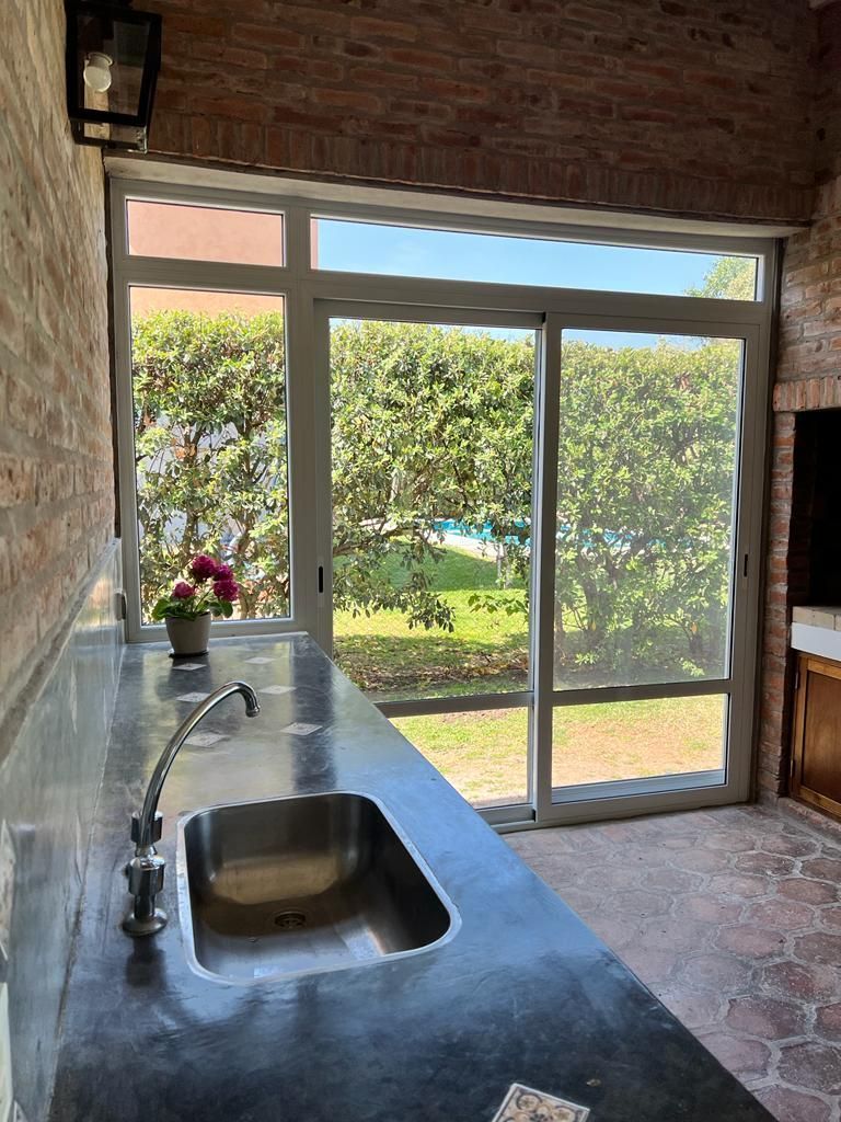 Encimera de cocina moderna con fregadero, frente a una puerta acristalada luminosa y con vistas al jardín