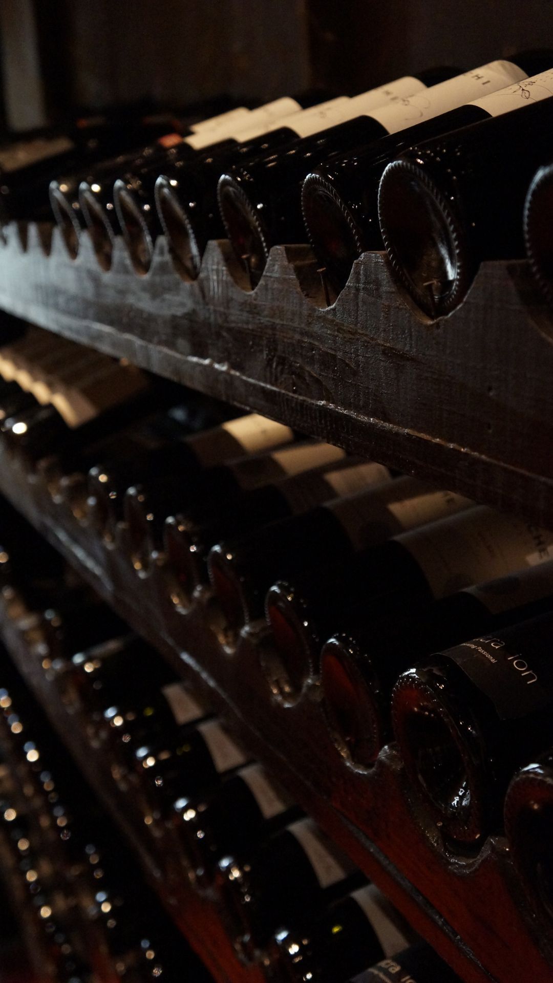 Une rangée de bouteilles de vin posées les unes sur les autres sur une étagère.