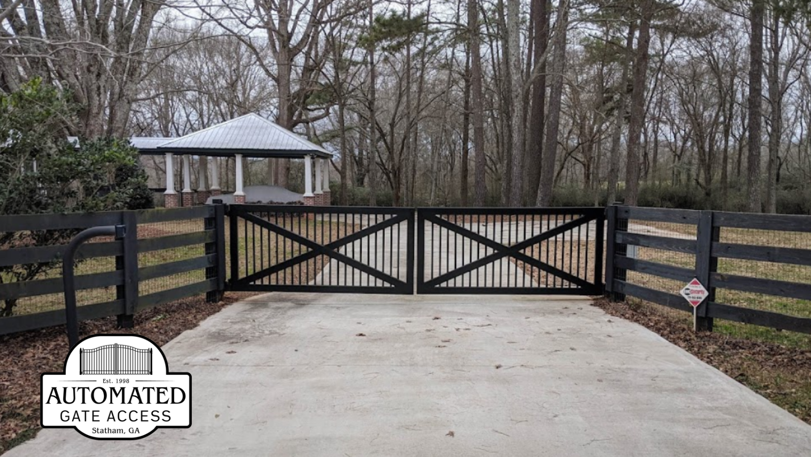 Wooden gate with pointed top pickets, open to a driveway.