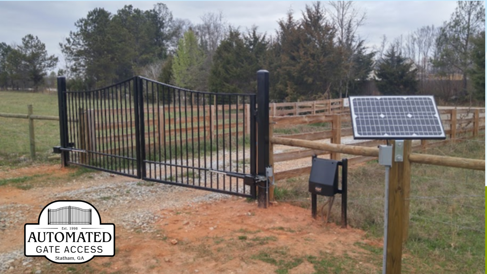Black metal automated gate, solar panel, and access box at a rural entrance.