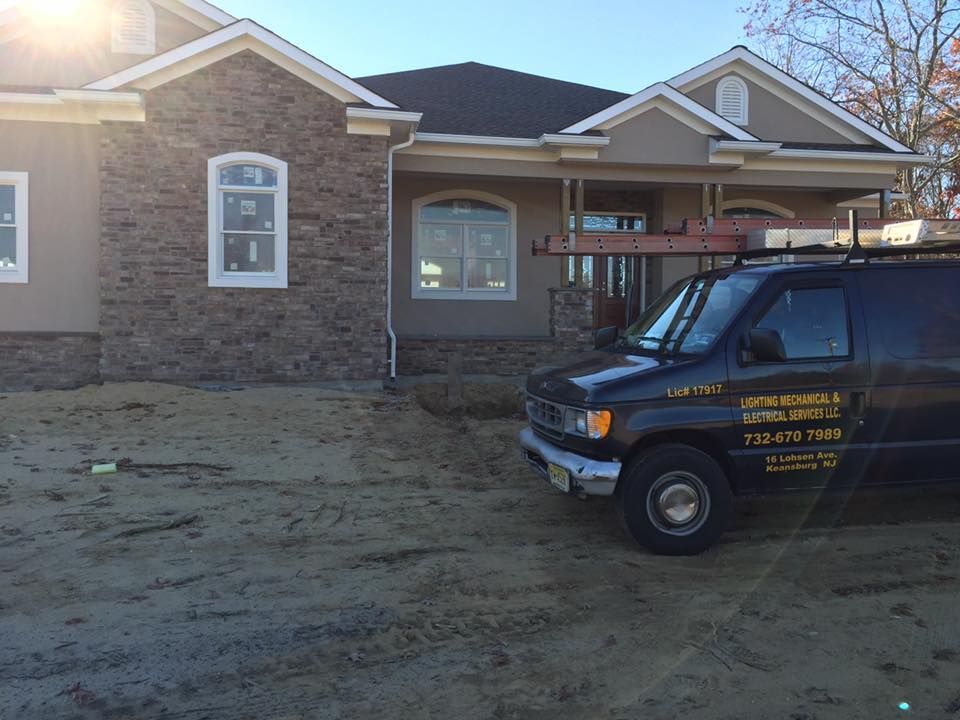 A black van parked in front of a house under construction on a sunny day.