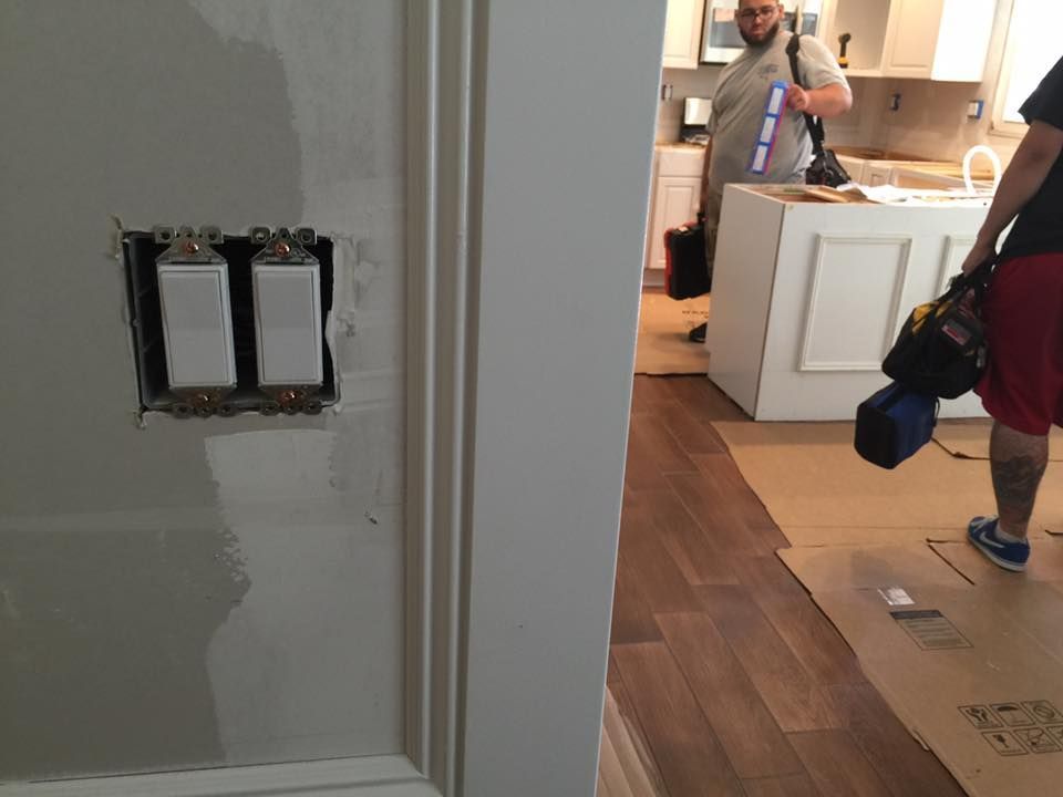 Electricians working on light switches in a home during a renovation.