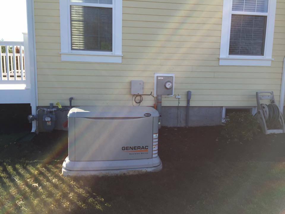 Generator next to a yellow house with windows and electrical components.