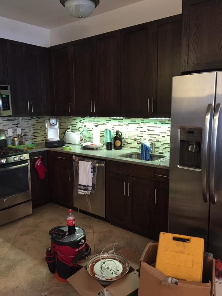 Kitchen with dark brown cabinets, stainless steel appliances, and boxes on the floor.