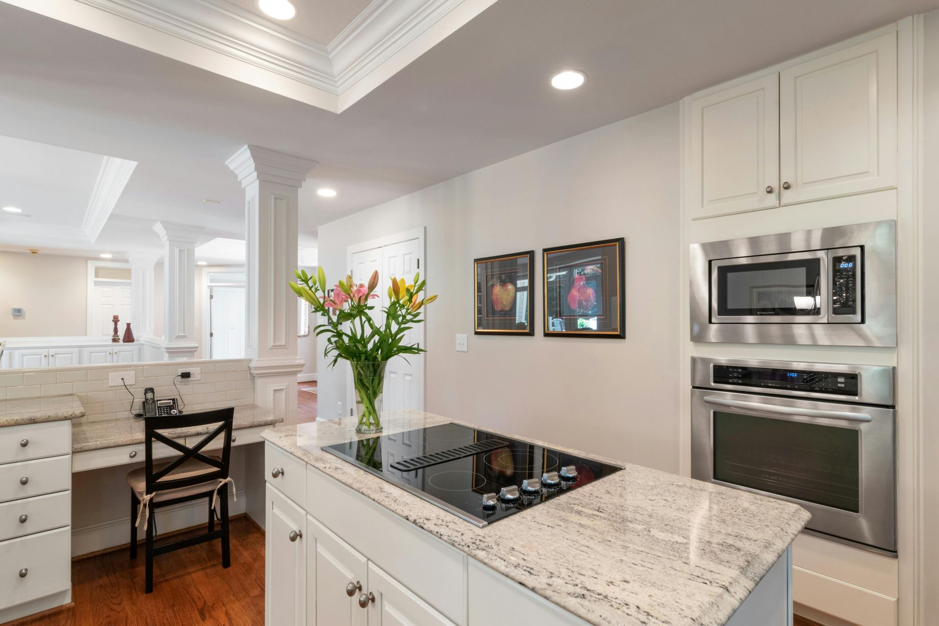 Modern kitchen with white cabinets, island with cooktop, and built-in appliances.