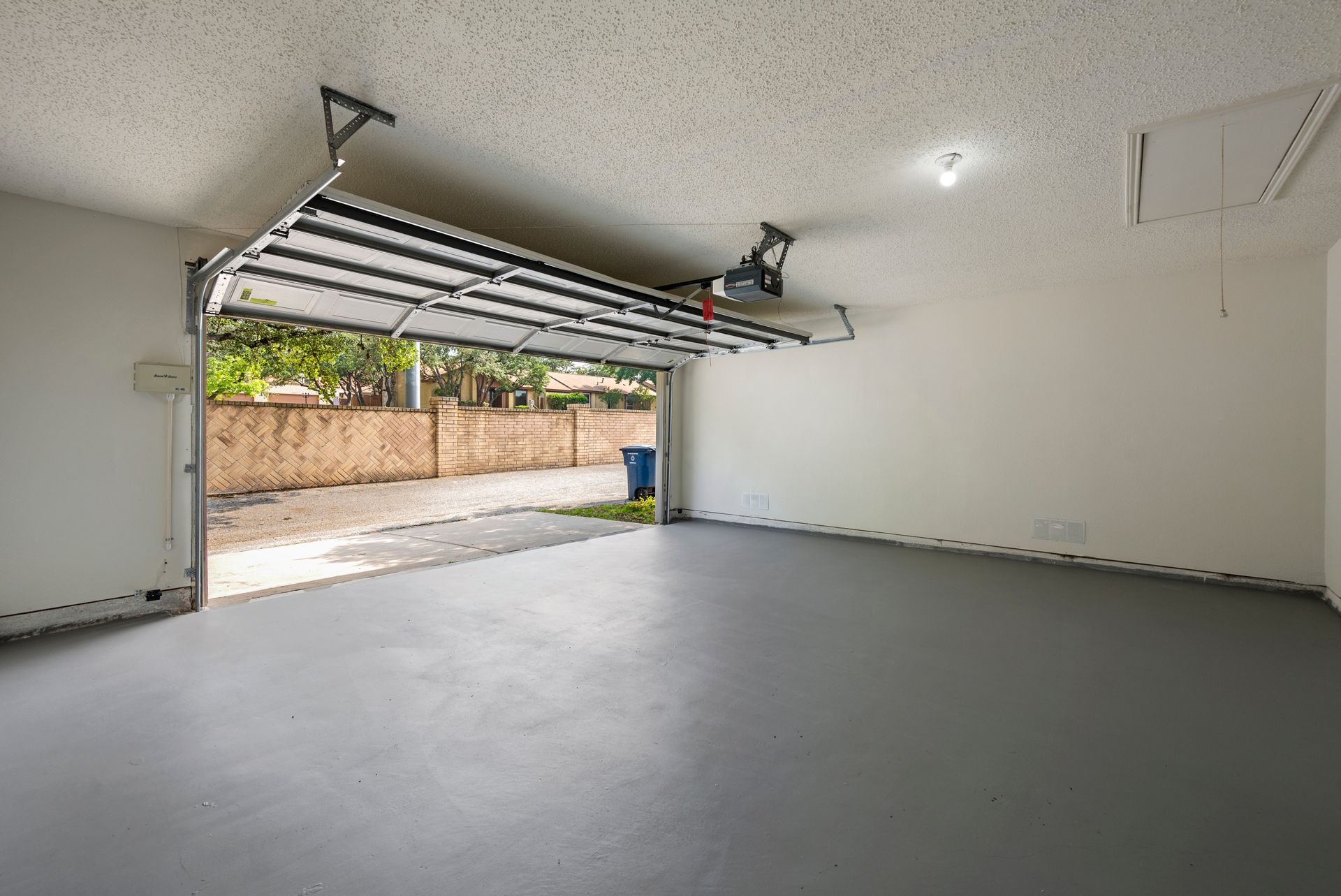 An Empty Garage With a Garage Door Open and a Gray Floor