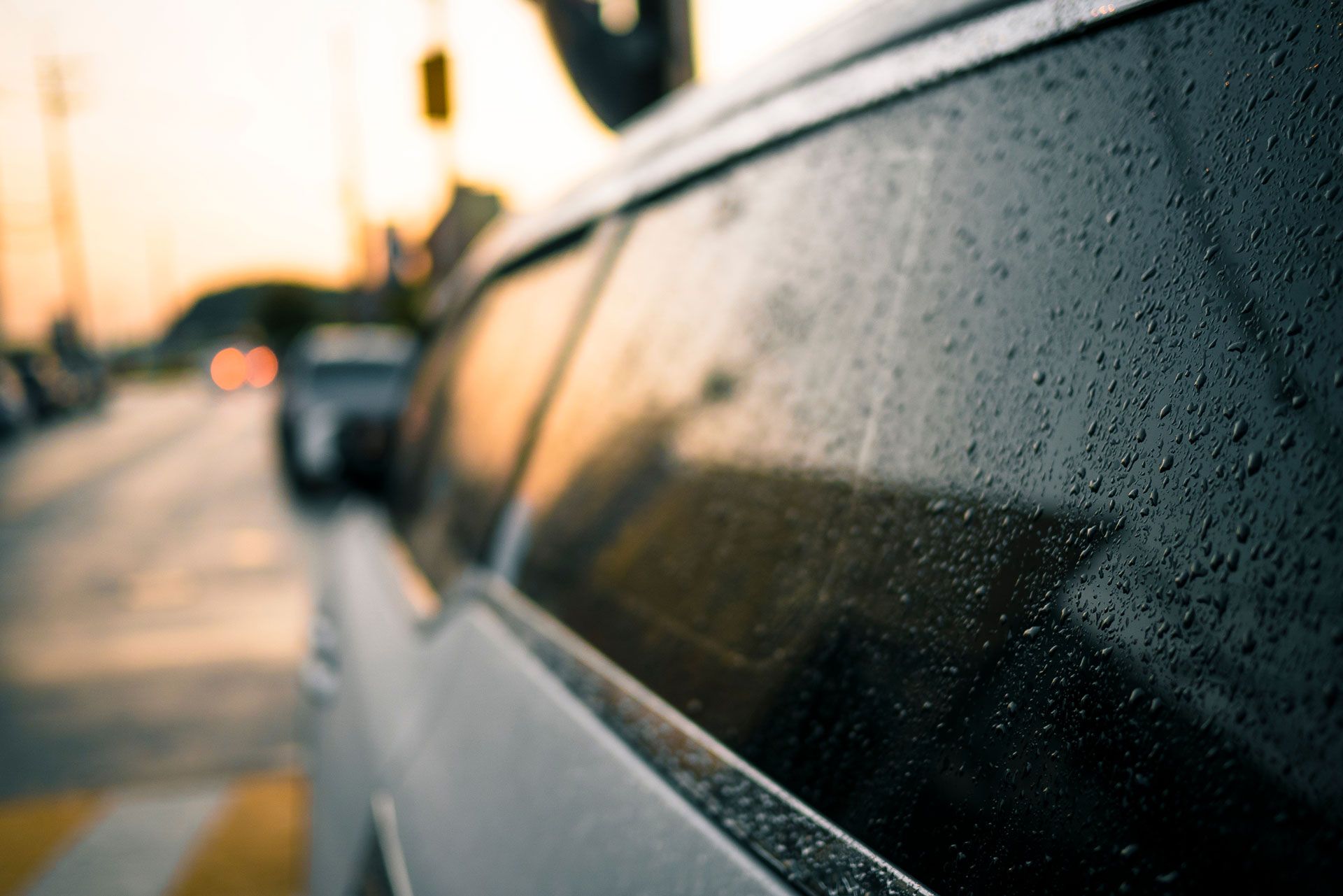 Van window with condensation, parked beside a road at dusk.