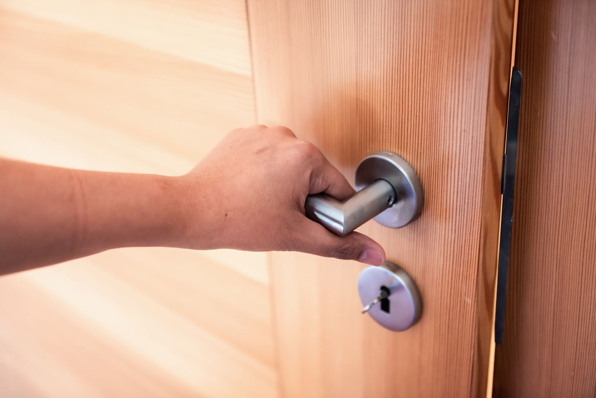 Una persona está abriendo una puerta de madera con un tirador.