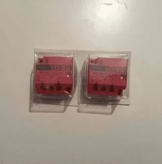 Due piccoli dispositivi elettronici rossi in una confezione di plastica trasparente su una superficie bianca