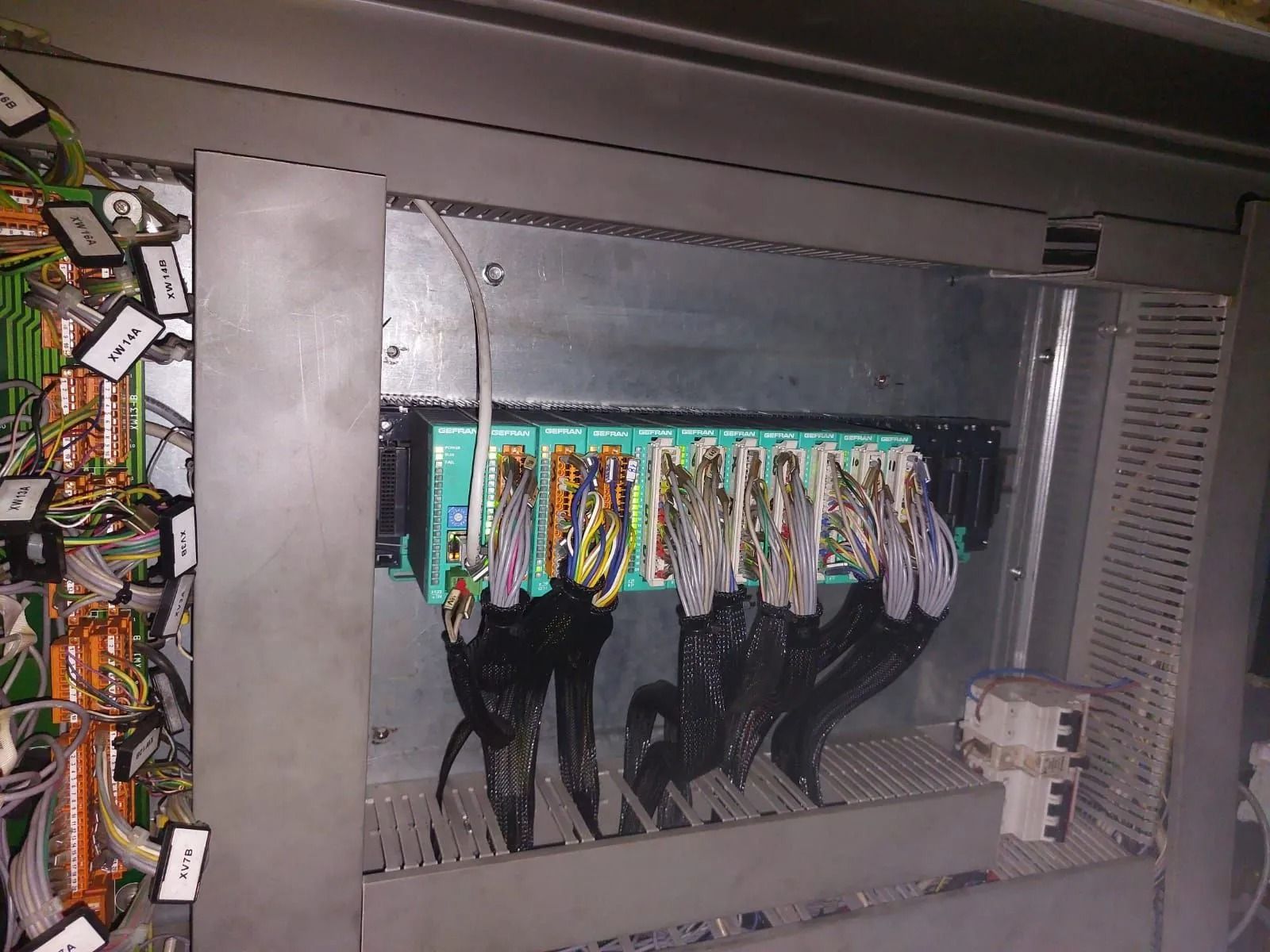 Quadro elettrico di controllo con file di fili multicolori all'interno di un armadio metallico.