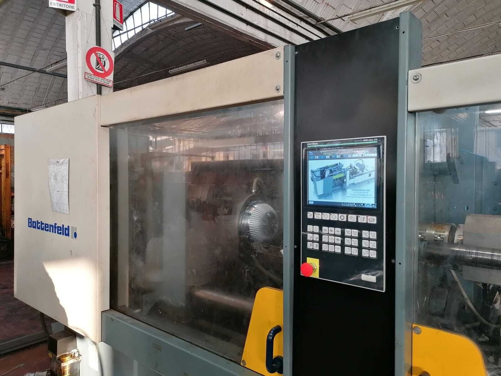 Macchina CNC industriale con pannello di controllo e cabina di sicurezza trasparente in un ambiente di fabbrica.