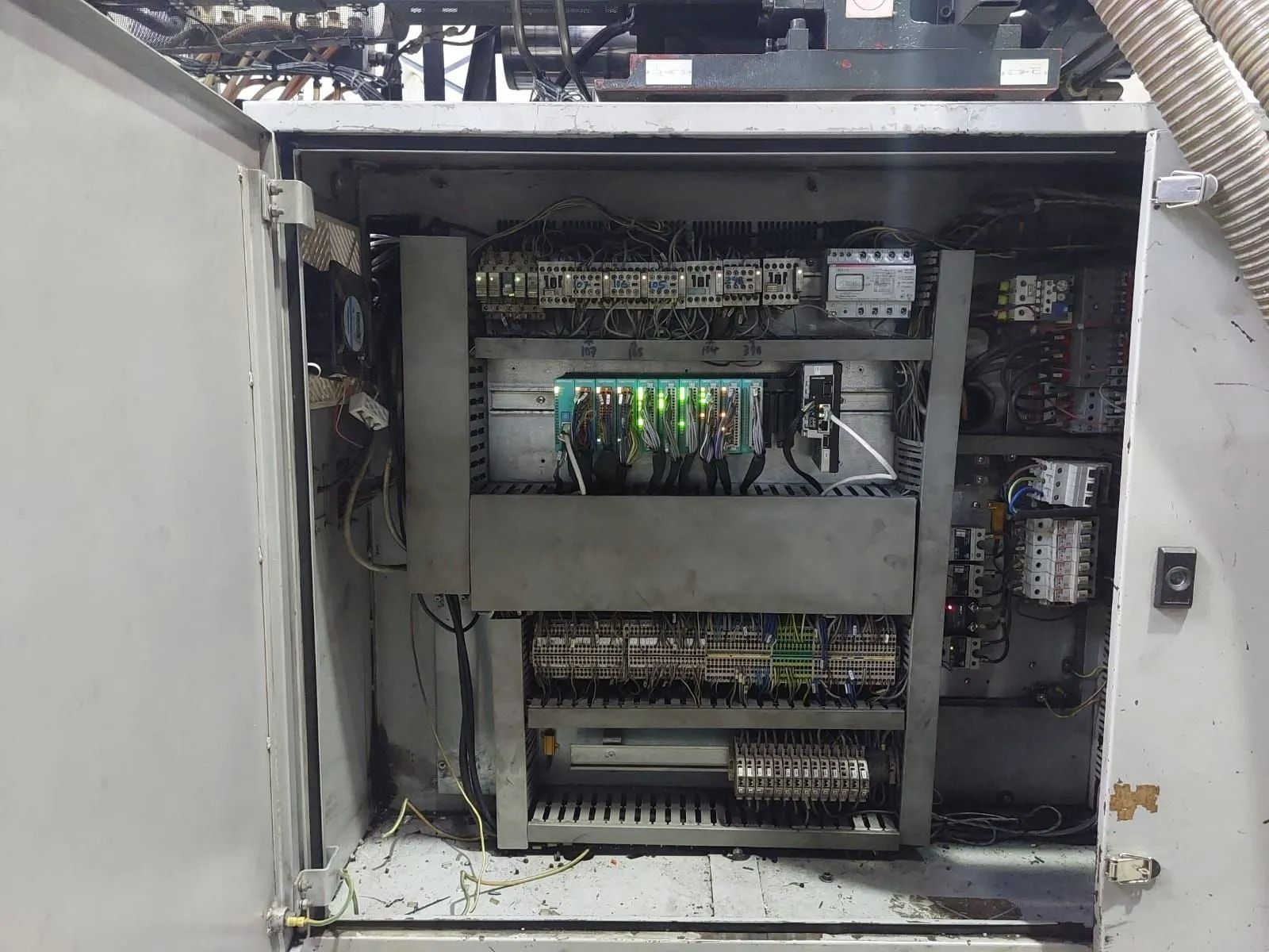Armadio elettrico aperto con cablaggio, circuiti stampati e spie luminose accese all'interno di un involucro metallico.