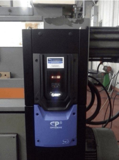 Unità di controllo industriale nera e blu montata su un macchinario in un ambiente di fabbrica.